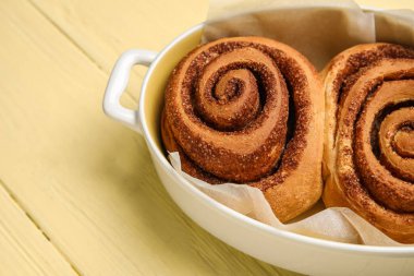 Sarı ahşap zemin üzerinde lezzetli tarçınlı börekler pişiriyorum.