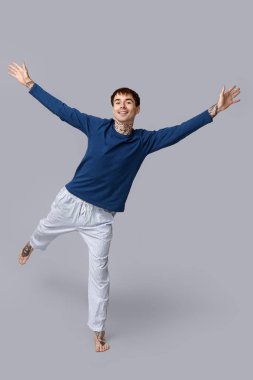 Gri arkaplanda pijamalı genç adam dövmesi var.