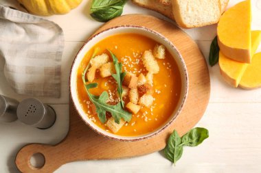 Bir kase lezzetli balkabağı kremalı çorba roka ve beyaz arka planda kızarmış ekmek.