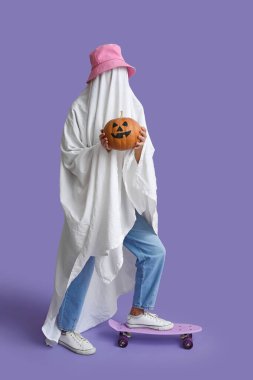 Cadılar Bayramı kostümlü kadın balkabağı ve leylak arka planda kaykay