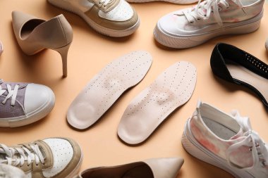 Renk arkaplan üzerinde ortopedik tabanlı ve farklı ayakkabılı kompozisyon