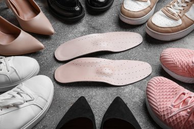 Farklı kadın ayakkabıları ve grunge arka planda ortopedik tabanlı kompozisyon, yakın plan.