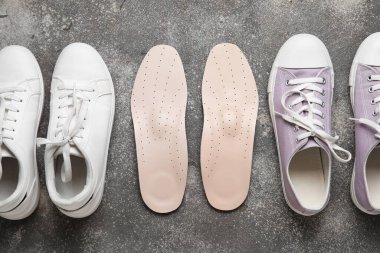 Şık kadın ayakkabıları ve grunge arka planda bir çift ortopedik taban, yakın plan.