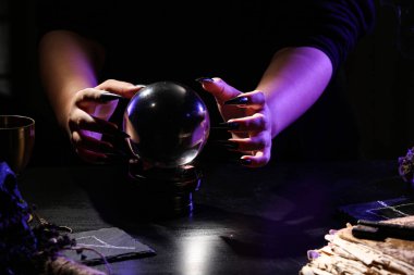 Karanlık masadaki kristal küreli cadı, yakın plan.