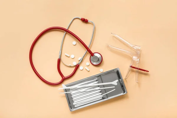 Stethoscope with gynecological speculum, pills and pap smear test tools on color background