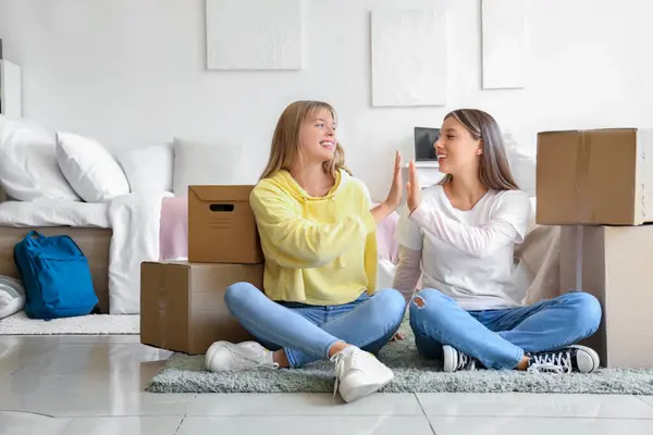 Female students giving each other high-five in dorm room on moving day