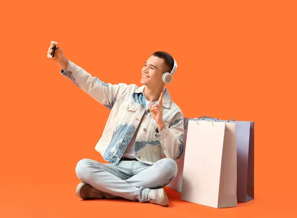 Jovem Fones Ouvido Com Sacos Compras Tirando Selfie Fundo Vermelho — Fotografia de Stock