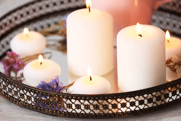 Tray with burning candles and flowers on table