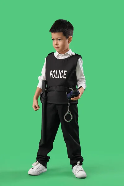 Cute little police officer with radio transmitter on green background