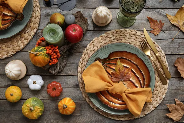 Autumn table serving with pumpkins and dry leaves on grey wooden table