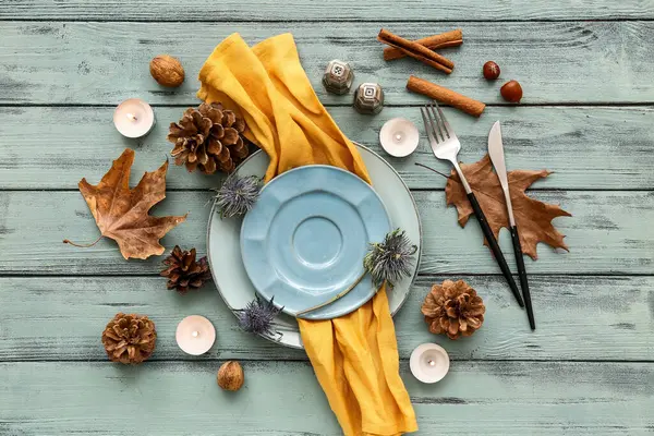 Autumn table setting with dried flowers, cones and burning candles on blue wooden background