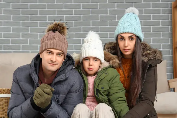 Frozen family in warm clothes at home with lack of heating