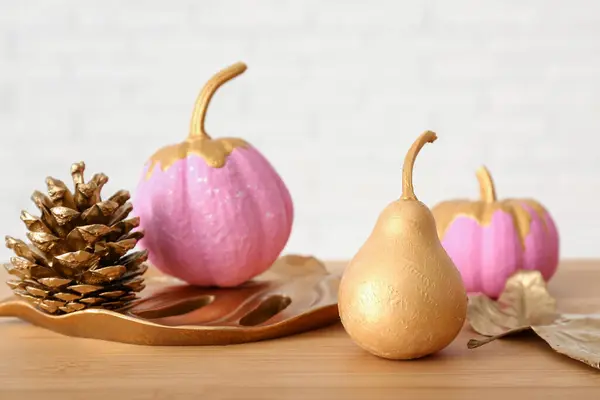 Painted pumpkins with pear and cone on wooden table
