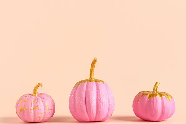 Pink painted pumpkins on orange background