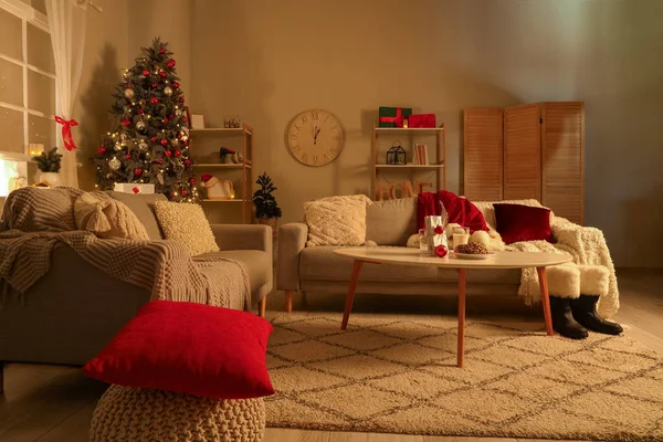 Interior of living room with sofas and Christmas cookies on table at night