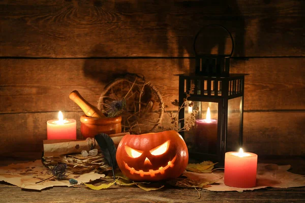 Cadılar Bayramı kompozisyonu kriko-fener, yanan mumlar, eski parşömenler ve ahşap masa yaprakları