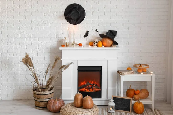Fireplace with Halloween decorations and pumpkins near white brick wall