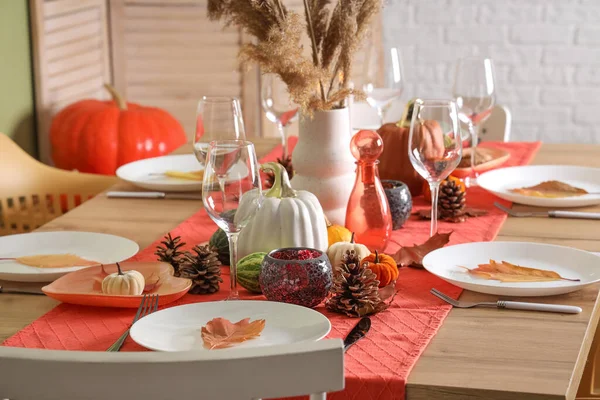 Autumn table setting with pumpkins, dry leaves and pine cones