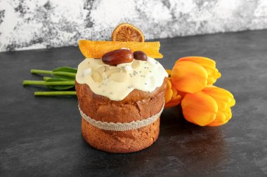 Sarı laleli Paskalya pastası açık grunge duvarının yanındaki karanlık masada.