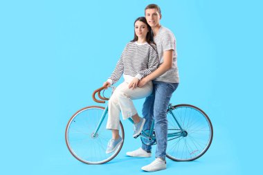 Mavi arka planda bisikleti olan mutlu genç çift.