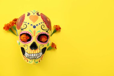 Meksika Ölüler Günü için boyanmış insan kafatası (El Dia de Muertos) ve sarı arka planda çiçekler