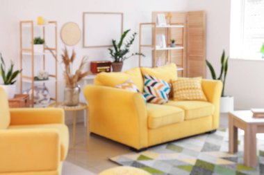 Sarı kanepe ve masalarla aydınlık oturma odasının içinde.