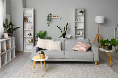 Gri kanepeli ve raf üniteli oturma odasının içi.