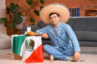 Evinde Meksika bayrağı olan şapkalı genç bir adam.
