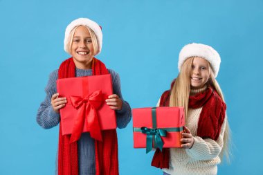 Mavi arka planda Noel hediyeleri olan küçük çocuklar