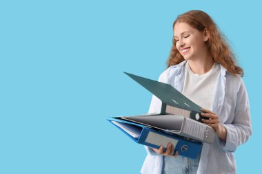 Mavi arkaplanda belge klasörleri olan genç bir kadın