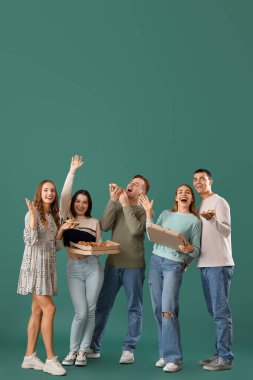 Yeşil arka planda lezzetli pizzaları olan bir grup genç arkadaş.
