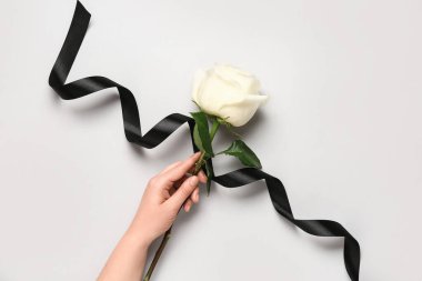 Beyaz arka planda gül ve siyah kurdeleli bir kadın.