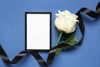 Fotoğraf çerçeveli siyah kurdele ve mavi arkaplanda beyaz gül