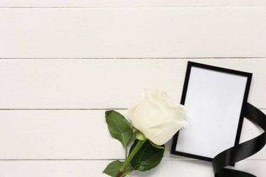 Fotoğraf çerçeveli gül ve beyaz ahşap arka planda siyah kurdele
