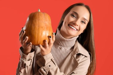 Kırmızı arka planda balkabağı olan genç kadın, yakın plan.