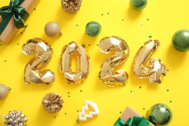 2024 yılbaşı balonları ve sarı arka planda hediyeler.