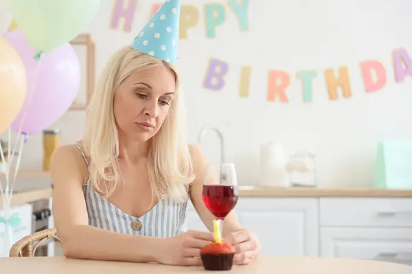 Sad mature woman celebrating Birthday in kitchen