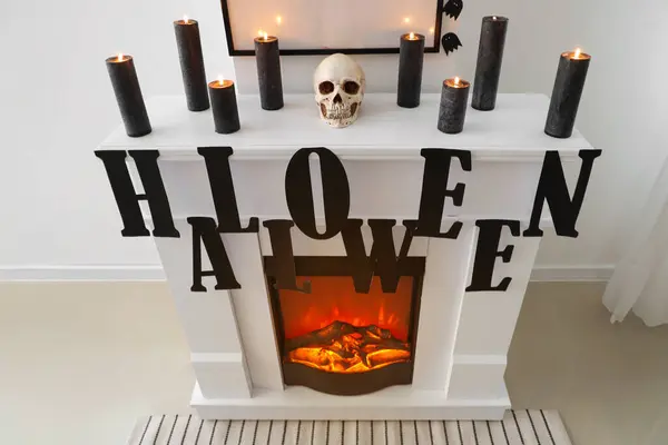 Fireplace with word HALLOWEEN, candles, skull and frame in room