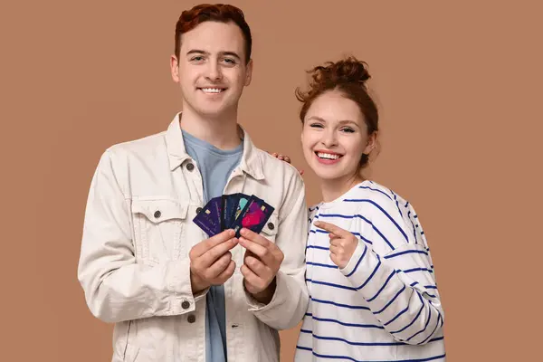 Młoda Para Wskazująca Karty Kredytowe Brązowym Tle — Zdjęcie stockowe