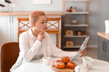Genç kadın mutfakta gazete okuma