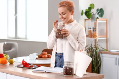 Mutfakta mısır gevreği kavanozu olan genç bir kadın.