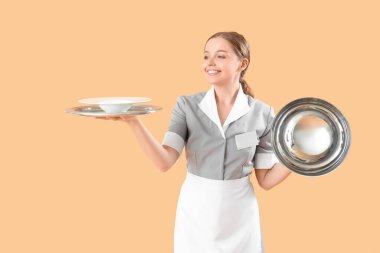 Boş tabağı, tepsisi ve bej arka planı olan genç bir garson.