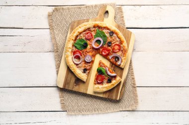 Beyaz ahşap arka planda fesleğenli ve domatesli lezzetli pizza.