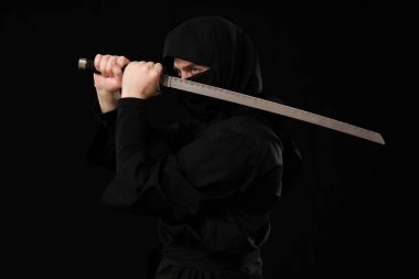 Siyah arka planda kılıç taşıyan erkek ninja.
