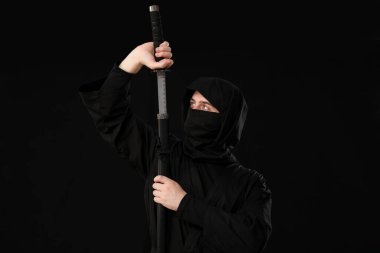 Siyah arka planda kılıç taşıyan erkek ninja.