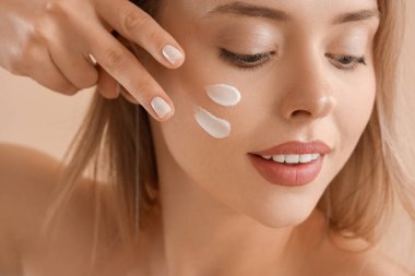 Yüzünde krem rengi bej arka planda güzel bir kadın, yakın plan.