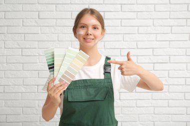 Beyaz tuğla arka planda renk örnekleri olan kadın dekoratör