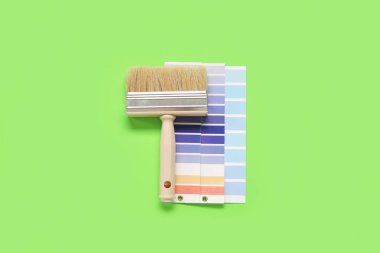 Yeşil arkaplanda birçok renk paleti ve fırça, üst görünüm