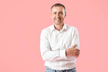 Pembe arka planda çapraz kollu yakışıklı olgun bir adamın portresi.