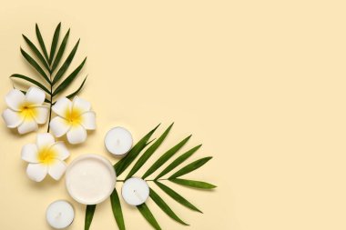 Krema kavanozu, mumlar, palmiye yaprakları ve çiçeklerle renklendirilmiş kompozisyon